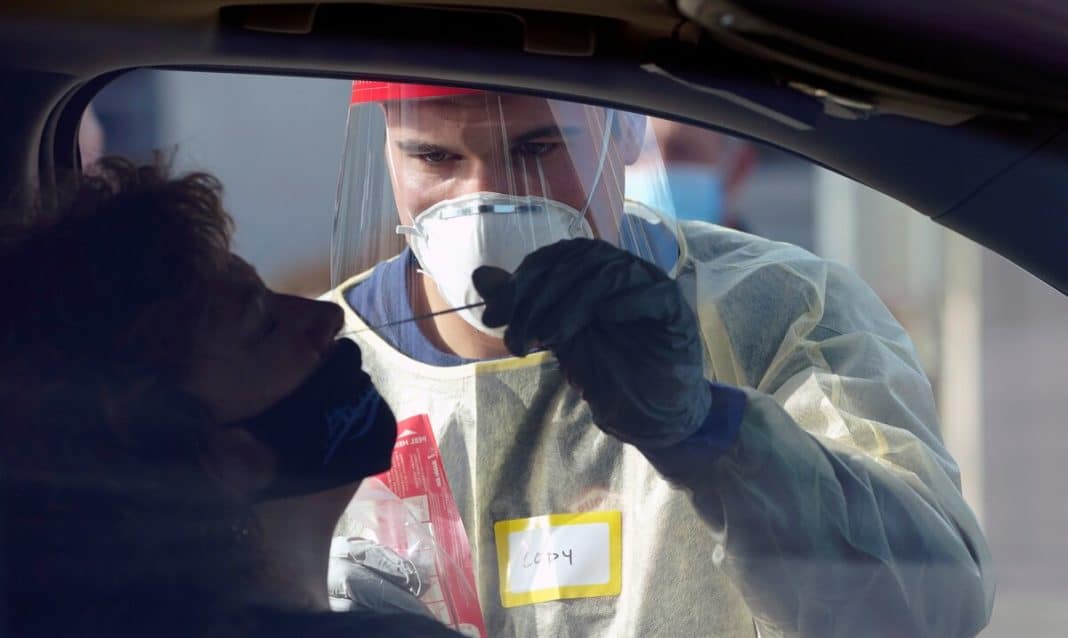 Un trabajador médico le toma la muestra nasal a una mujer para realizar la prueba molecular de COVID-19.