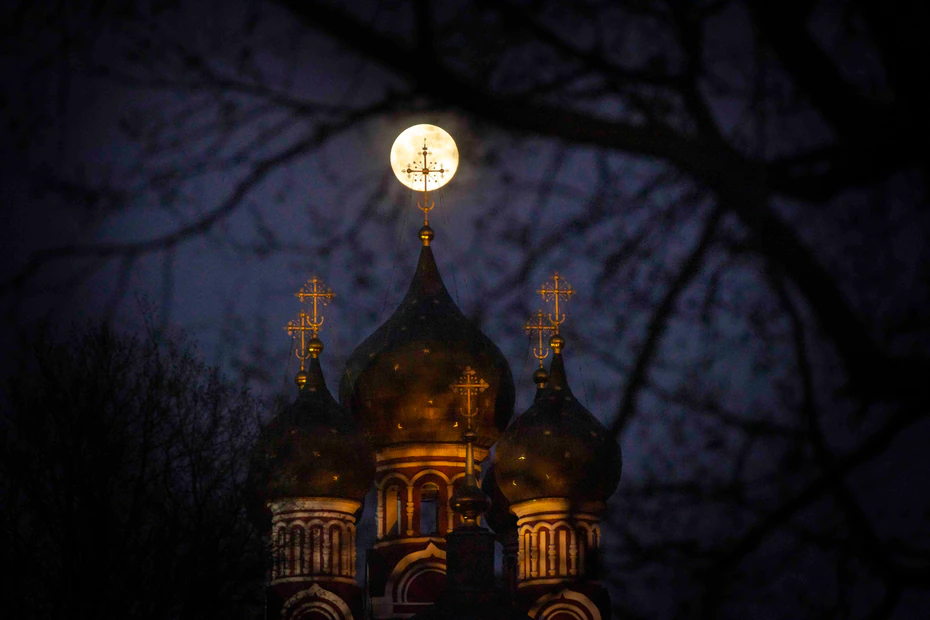 La superlune se lève derrière la croix illuminée d'une église chrétienne orthodoxe à Moscou, en Russie.