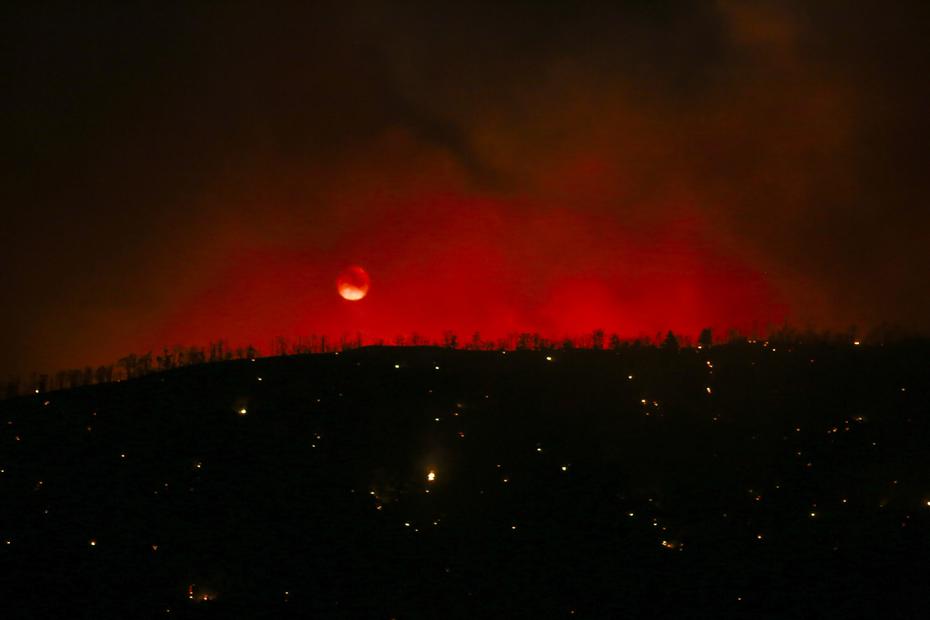 La lune est vue alors que l'incendie de Sheep brûle à Wrightwood, en Californie, le lundi 13 juin 2022. (AP Photo/Ringo H.W. Chiu)